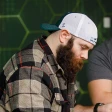 Adult student wearing hat backwards and plaid shirt studying cybersecurity